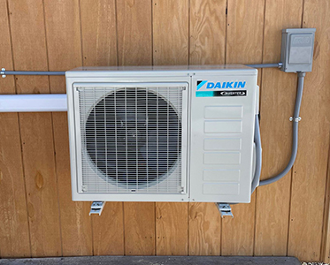 Daikin brand air conditioning unit mounted on a wood-paneled wall.