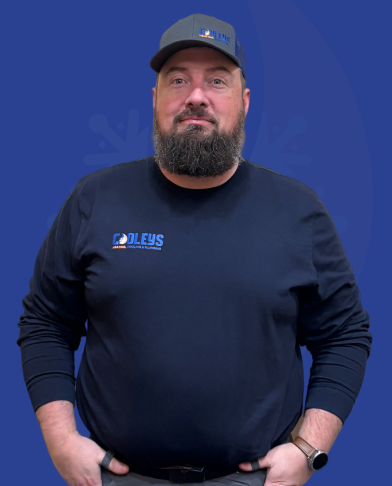 Man with beard wearing a navy blue long-sleeve shirt and matching cap with 'Doleys' logo, standing against a blue background.