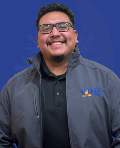 Smiling man wearing glasses and a gray jacket with a heating company logo on a blue background.