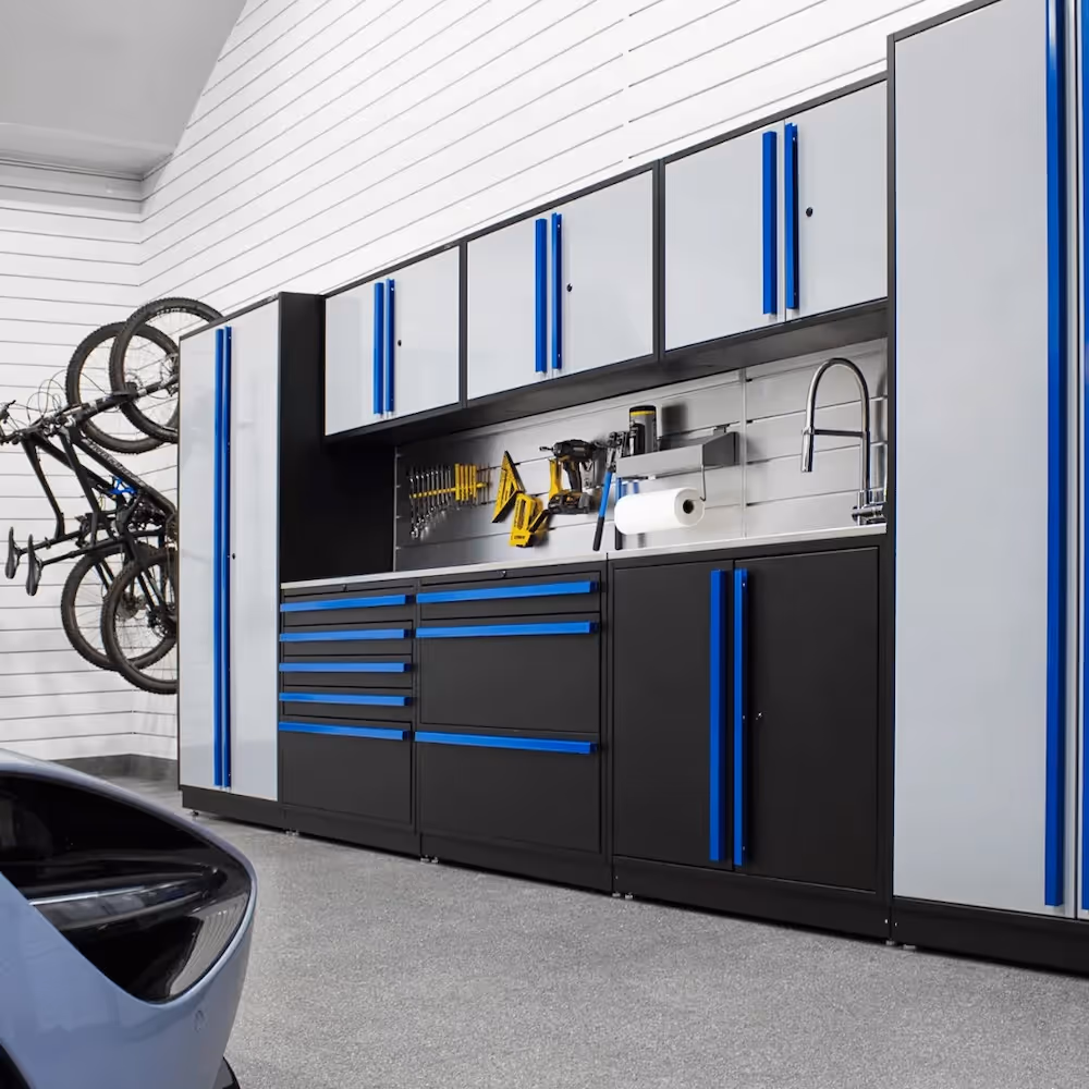 Modern garage storage system with gray and black cabinets featuring blue handles, a bike rack with two bikes mounted on the wall, and various tools organized on a pegboard.