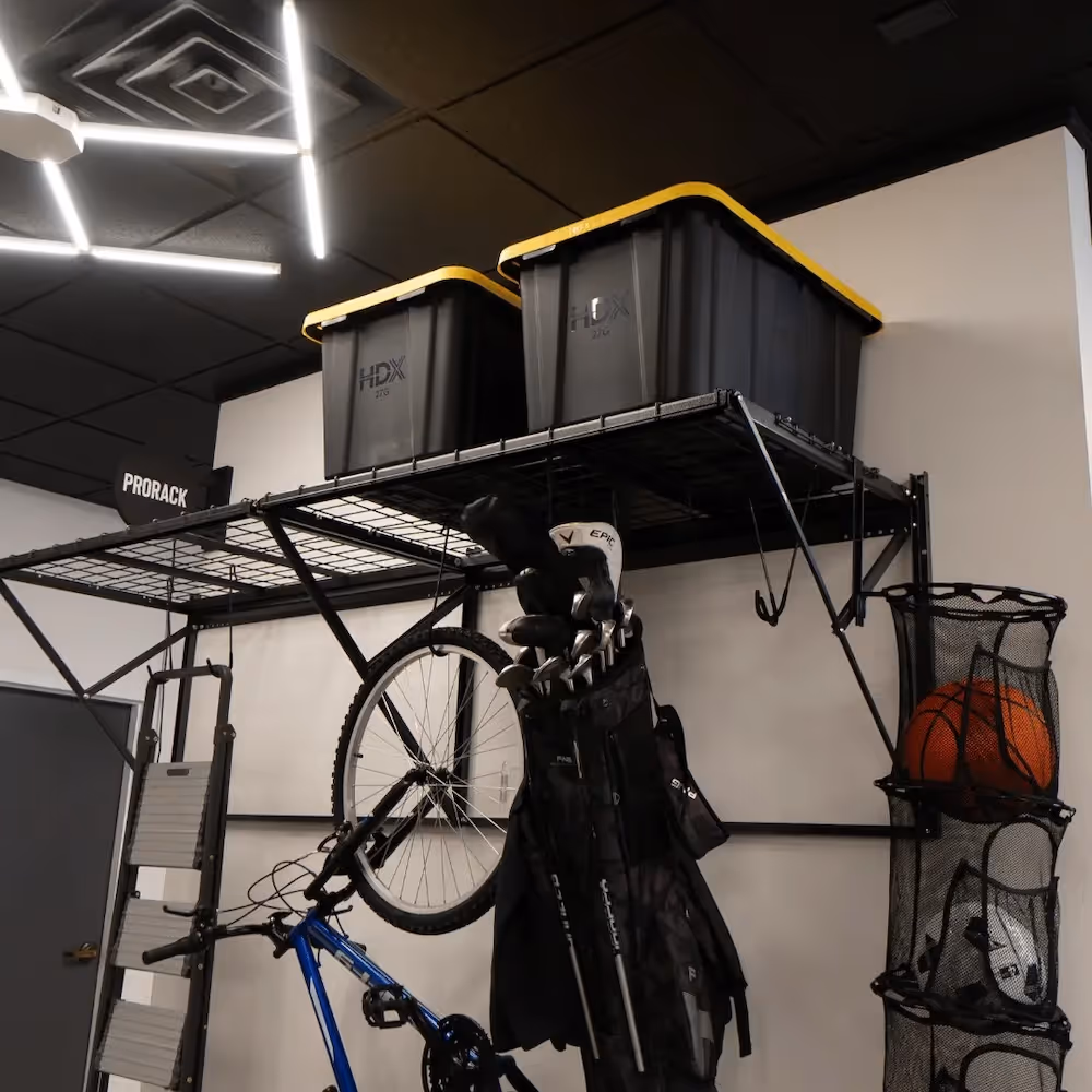 Metal storage rack holding two large plastic bins, a bicycle, and a golf bag with clubs under bright ceiling lights.