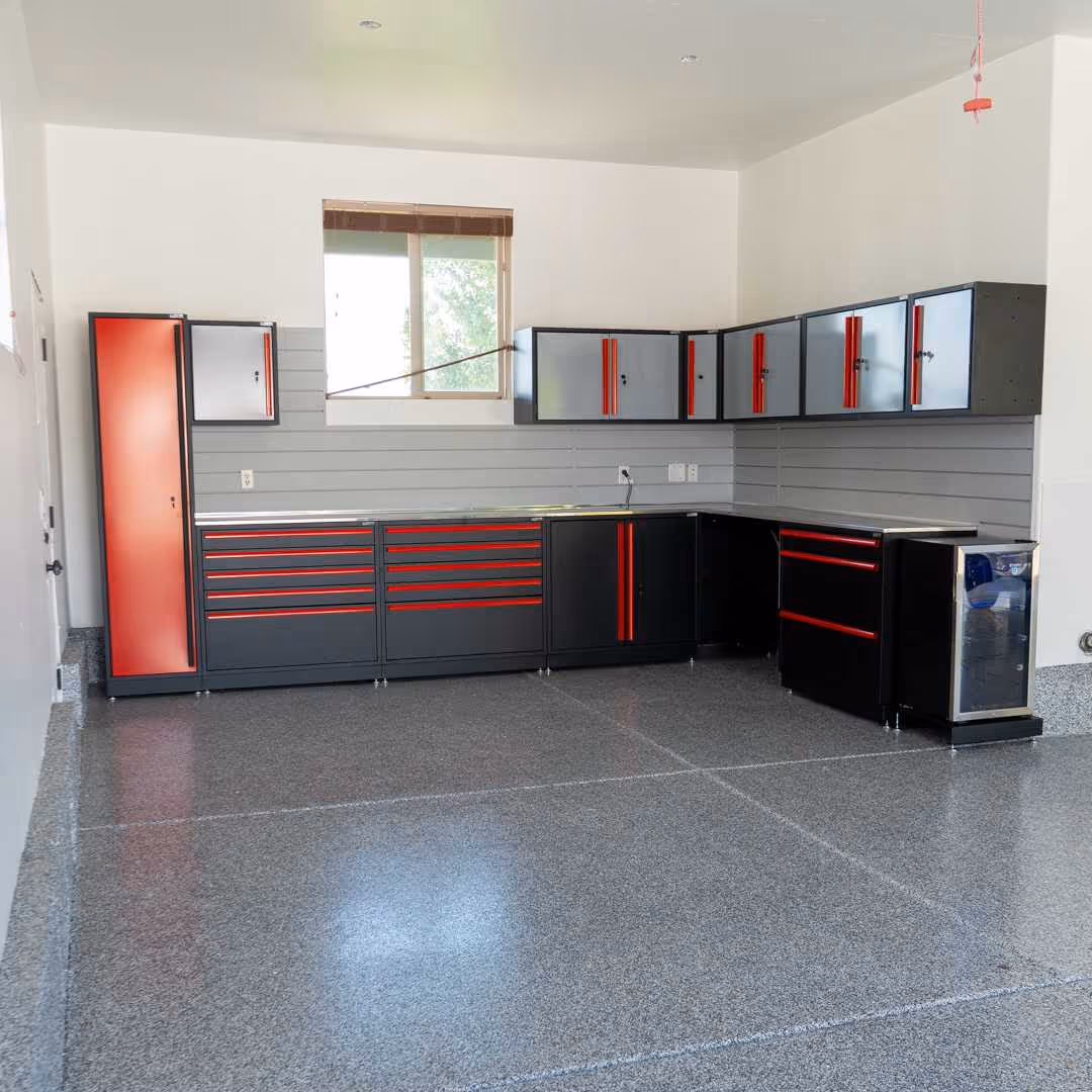 Modern garage interior with gray and red storage cabinets, epoxy floor, and a window on white walls.