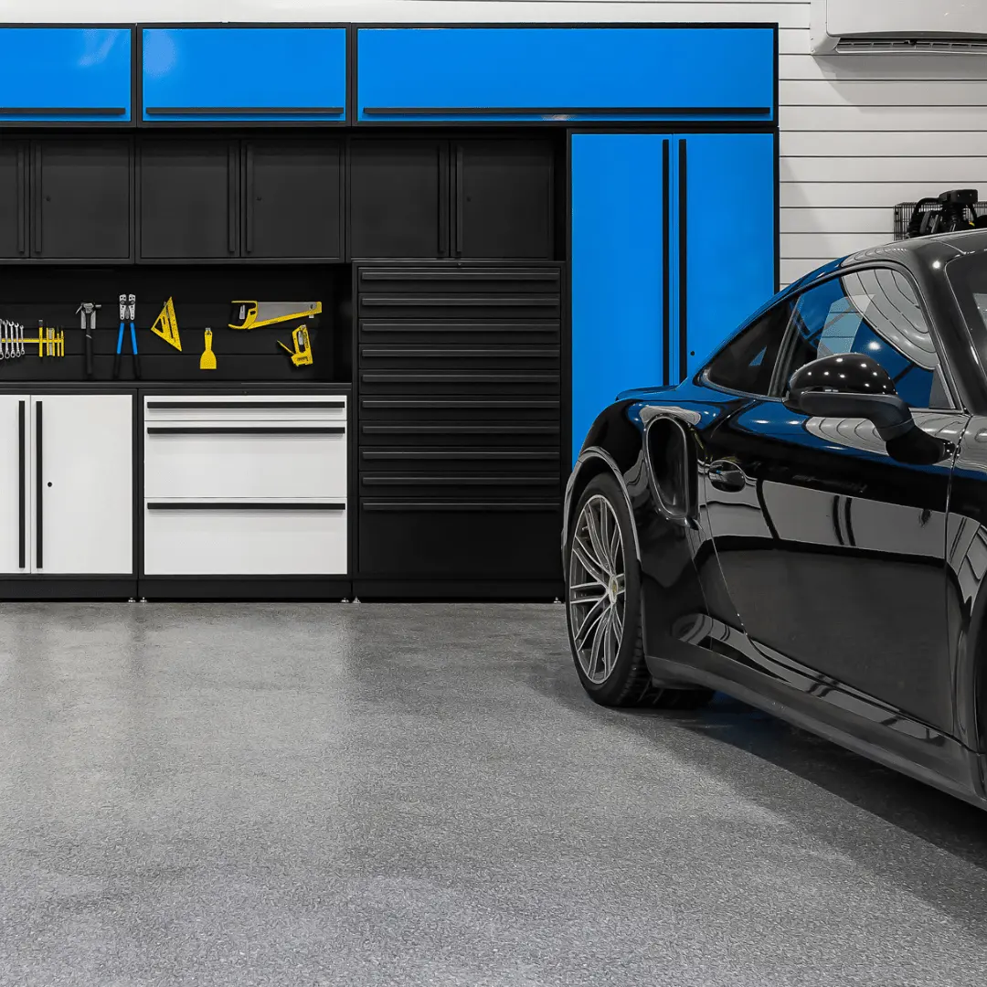 Modern garage interior with black and blue storage cabinets along the wall and a black sports car parked on a polished concrete floor.