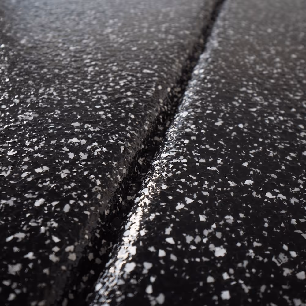 Close-up of black speckled epoxy surface with a central seam and glossy finish.