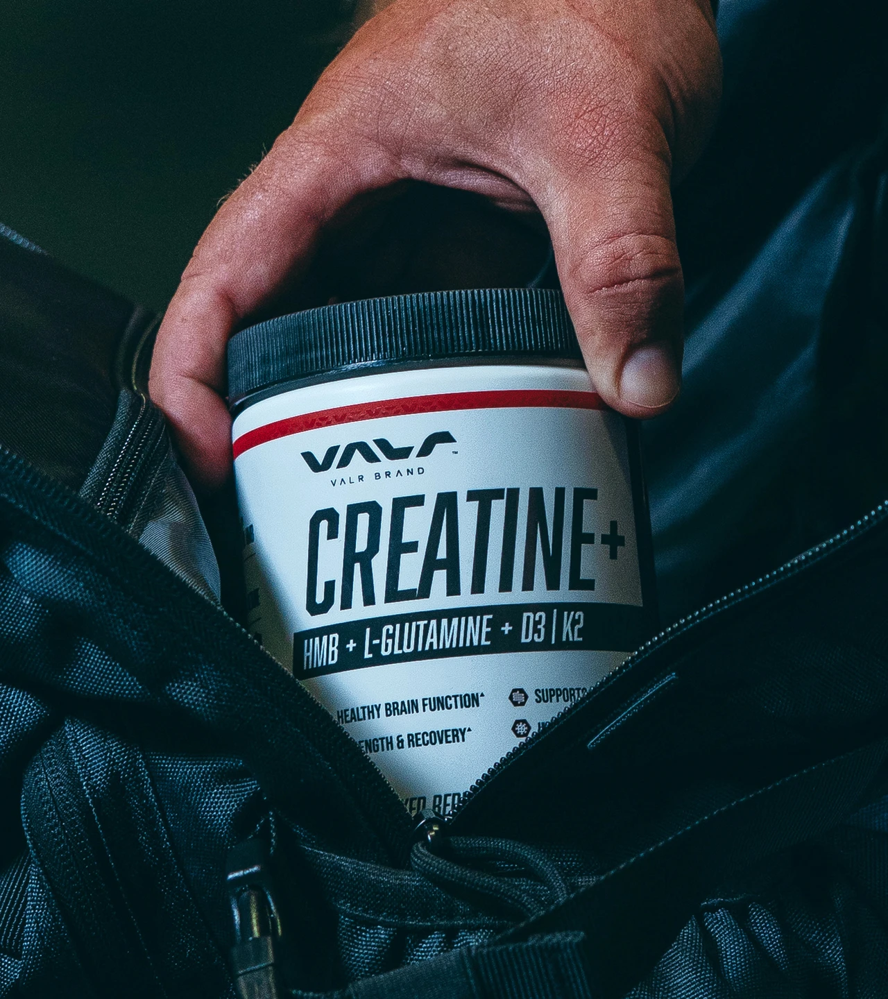 Athlete reaching into a gym bag for a VALR Creatine+ jar.