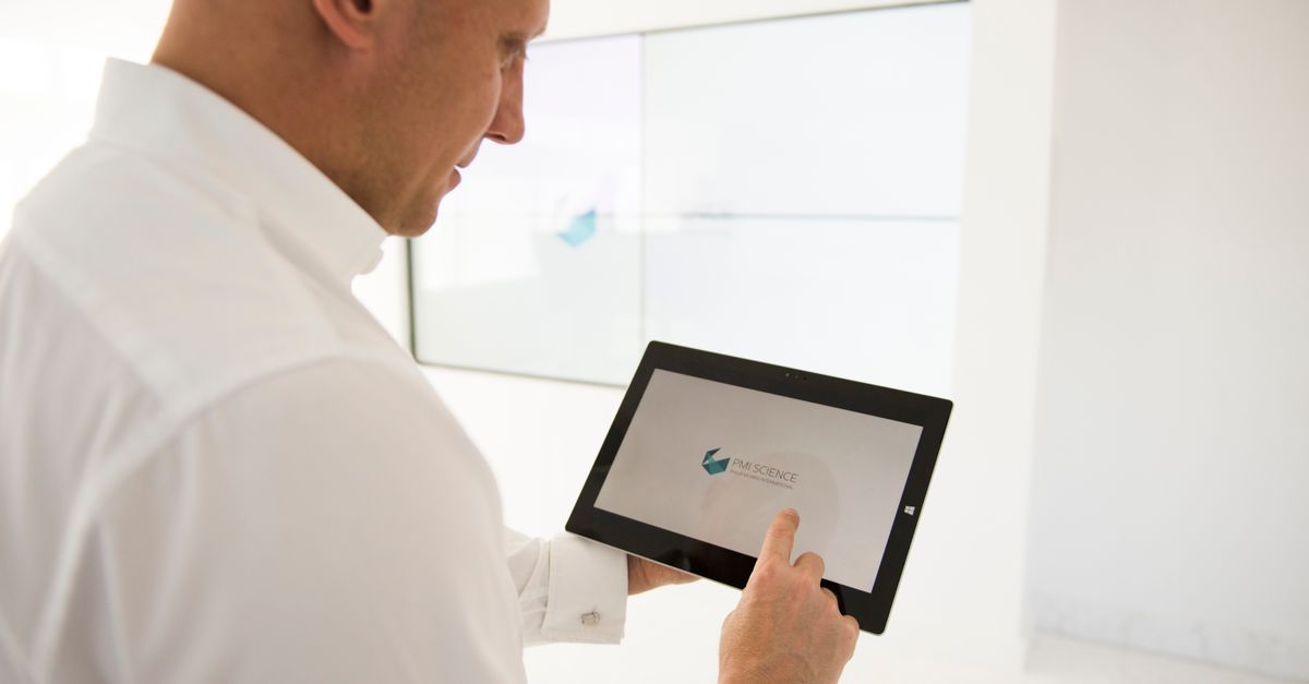 Person im weißen Hemd hält ein Tablet in der Hand