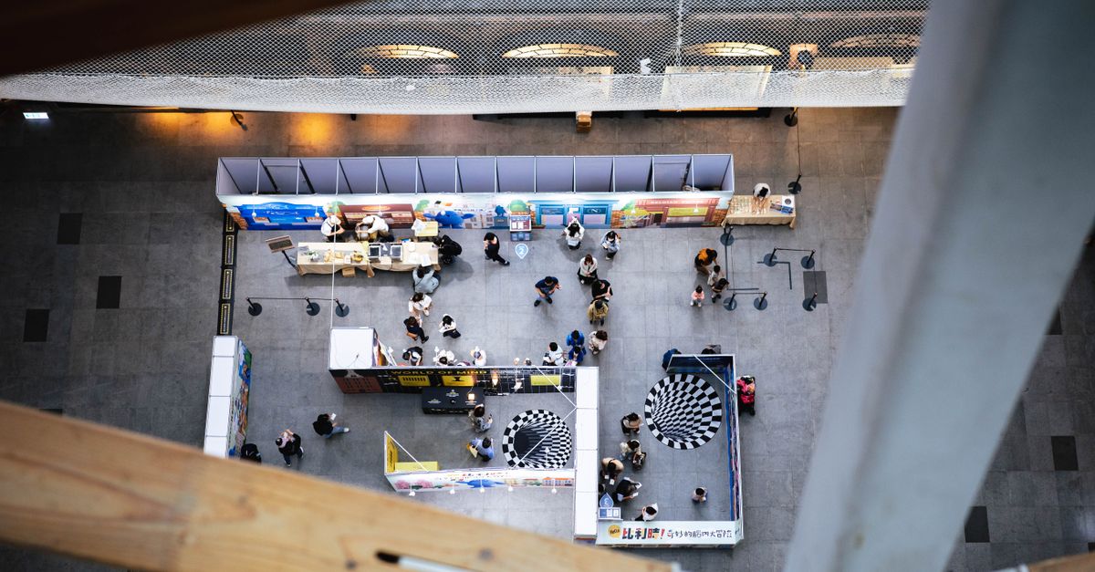 Blick von oben auf ein Foyer mit Ständen und Besuchern