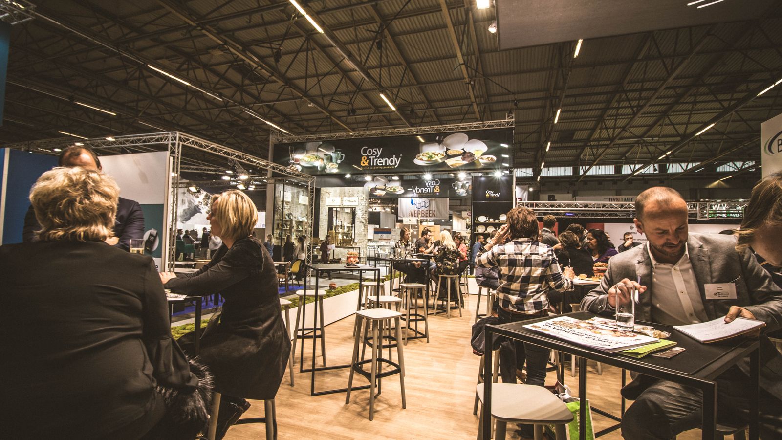 Messehalle mit Ausstellerständen und Fachbesuchern im Gespräch