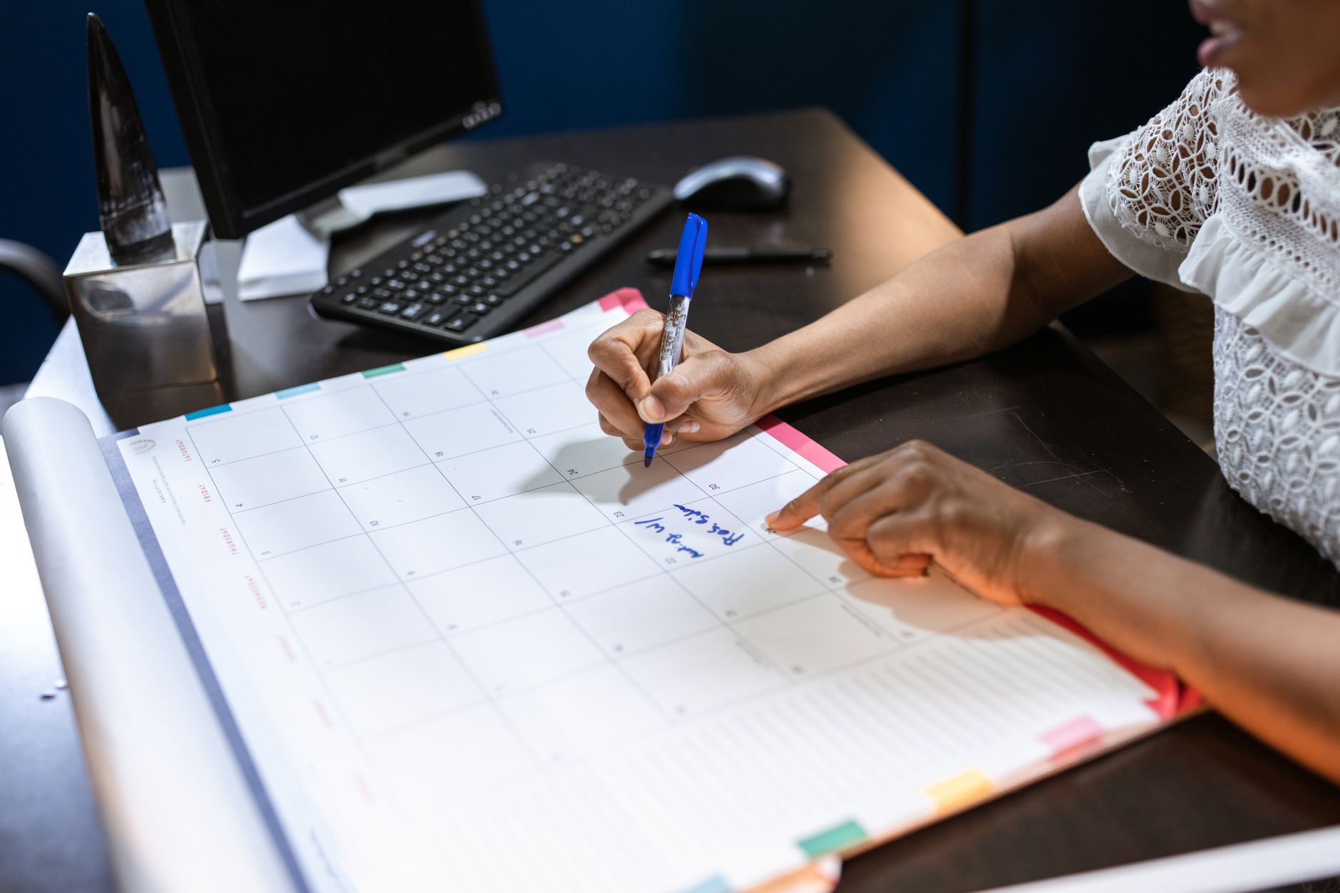 Person trägt mit einem Stift Notizen in einen Tischkalender ein