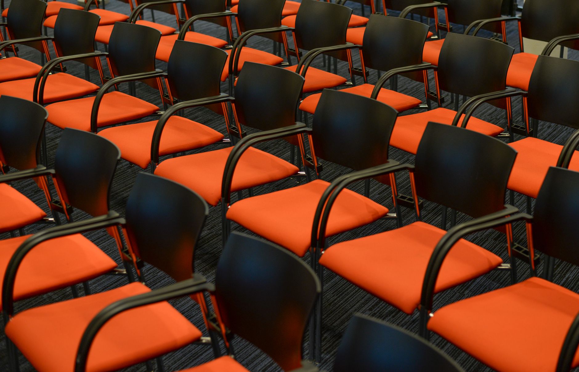 Leere orangefarbene Sitzreihen in einem Kongresssaal