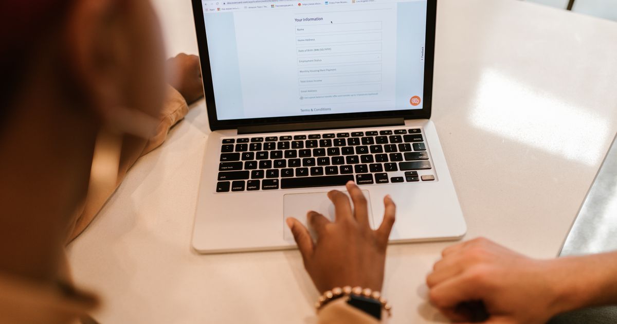 Zwei Personen füllen gemeinsam ein Onlineformular am Laptop aus