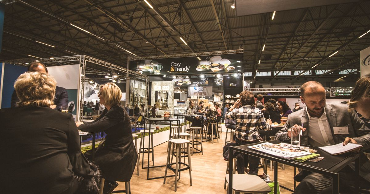 Messehalle mit Ausstellerständen und Fachbesuchern im Gespräch