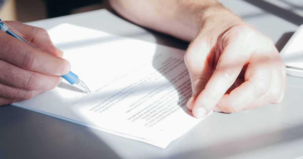 Hände unterschreiben einen Vertrag mit einem blauen Stift