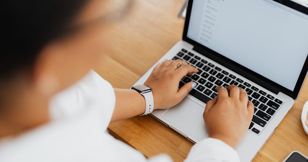 Hände tippen einen Text auf einer Laptoptastatur