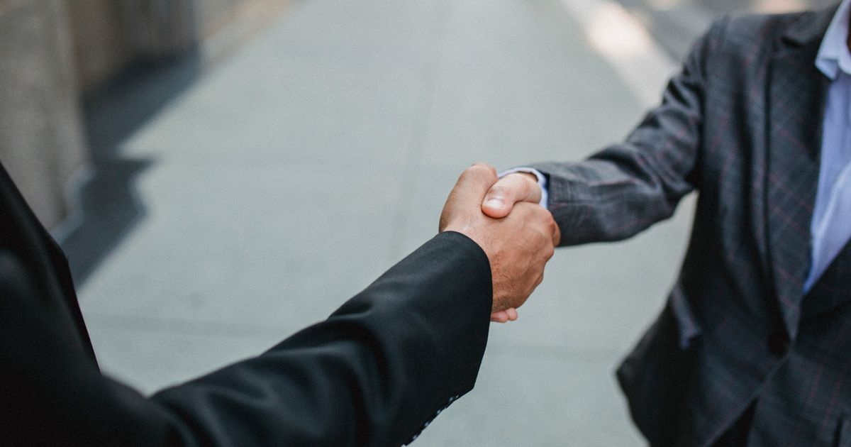 Zwei Personen geben sich im Freien die Hand