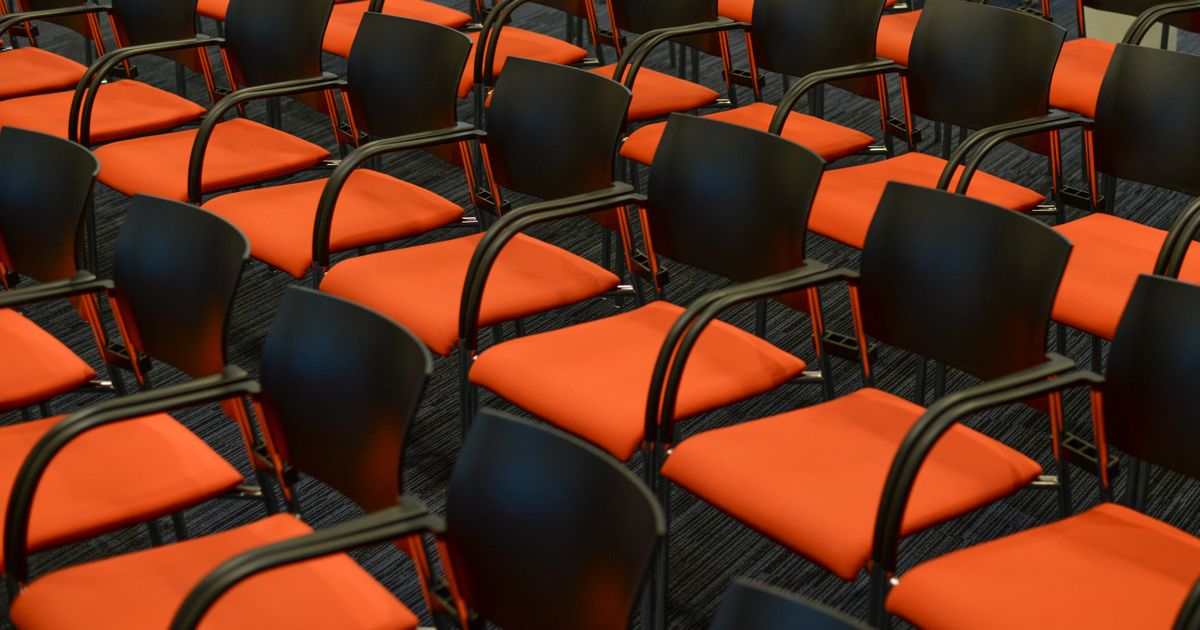 Leere orangefarbene Sitzreihen in einem Kongresssaal