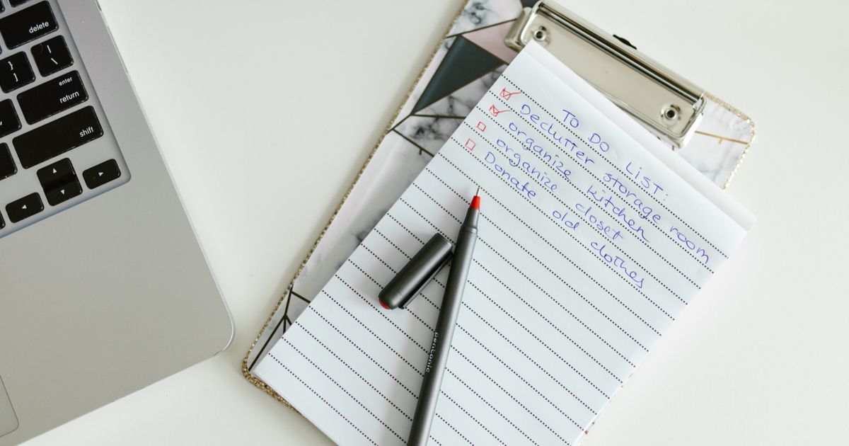 Klemmbrett mit handschriftlicher Liste neben einem Laptop