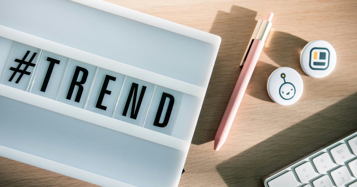 Leuchtkasten mit dem Schriftzug TREND neben Stift und Tastatur