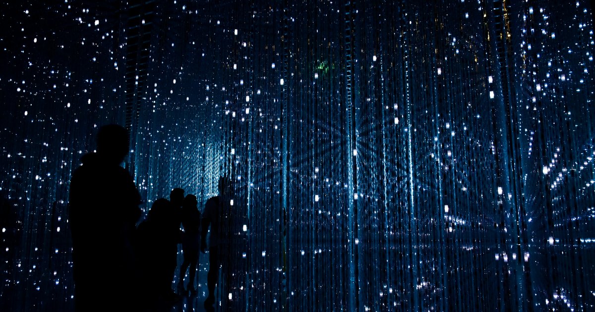 Silhouetten von Menschen vor einer blauen Lichtinstallation