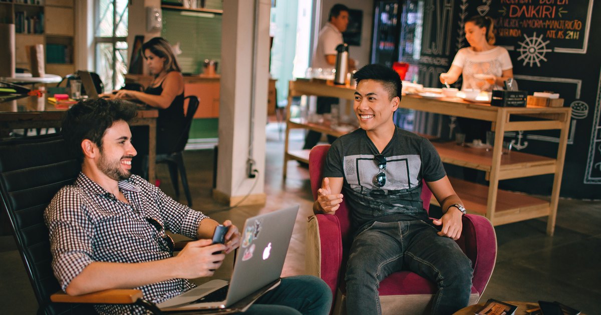Zwei Männer mit Laptops im Gespräch in einem Coworking-Raum