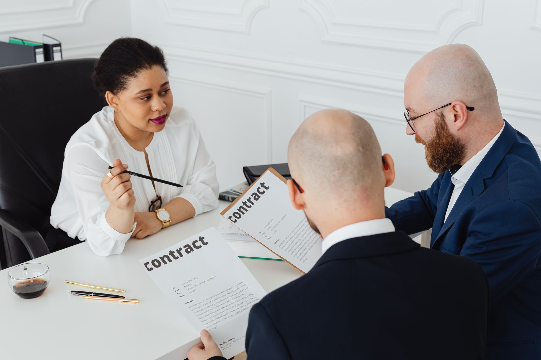 Drei Personen besprechen einen Vertrag an einem Besprechungstisch
