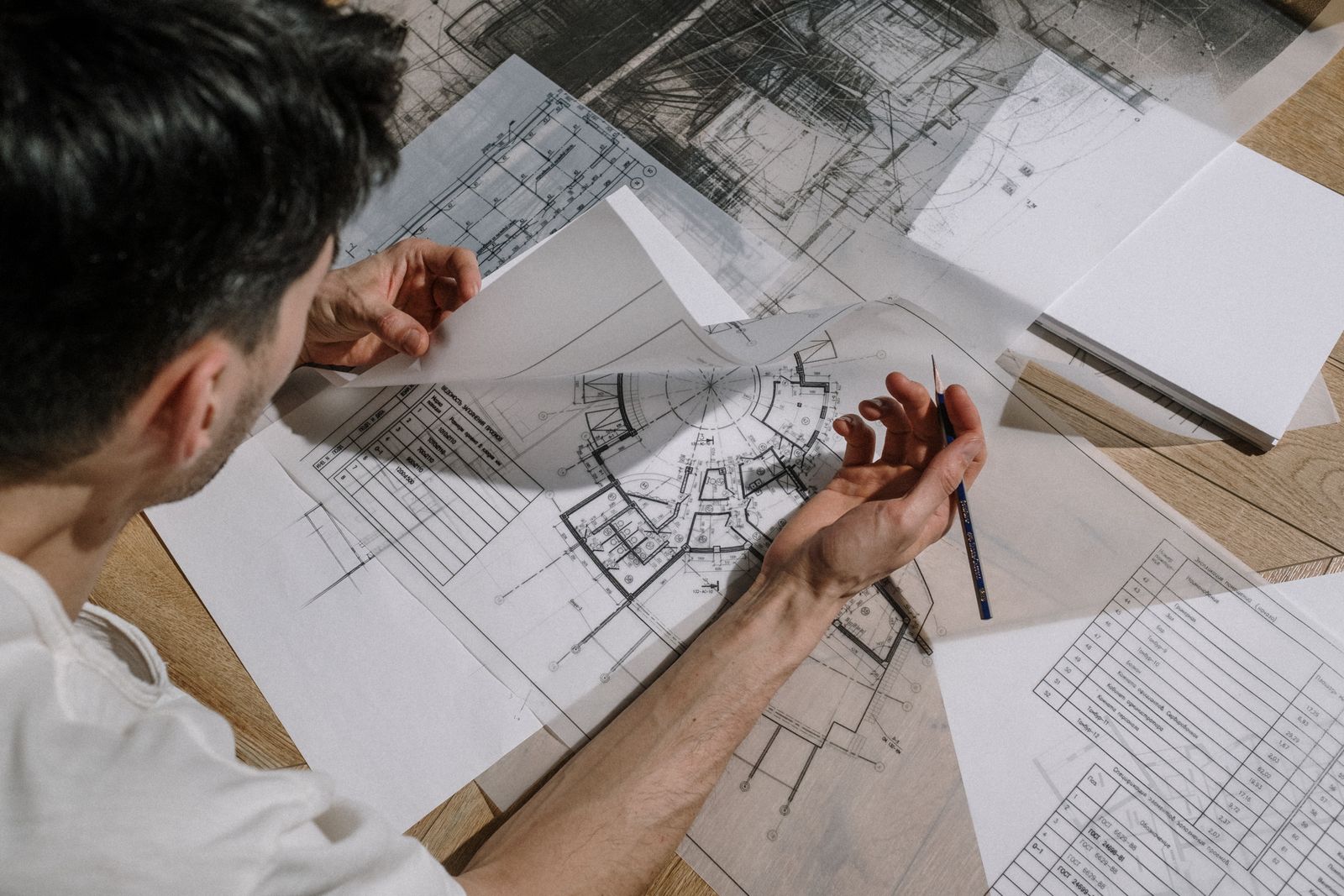 Person zeichnet mit einem Stift auf einem großformatigen Bauplan