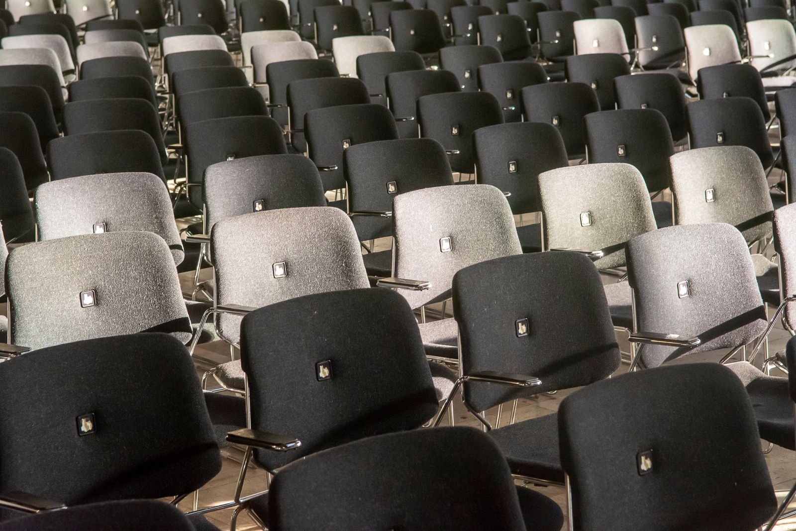 Reihen schwarzer und grauer Stühle in einem leeren Saal