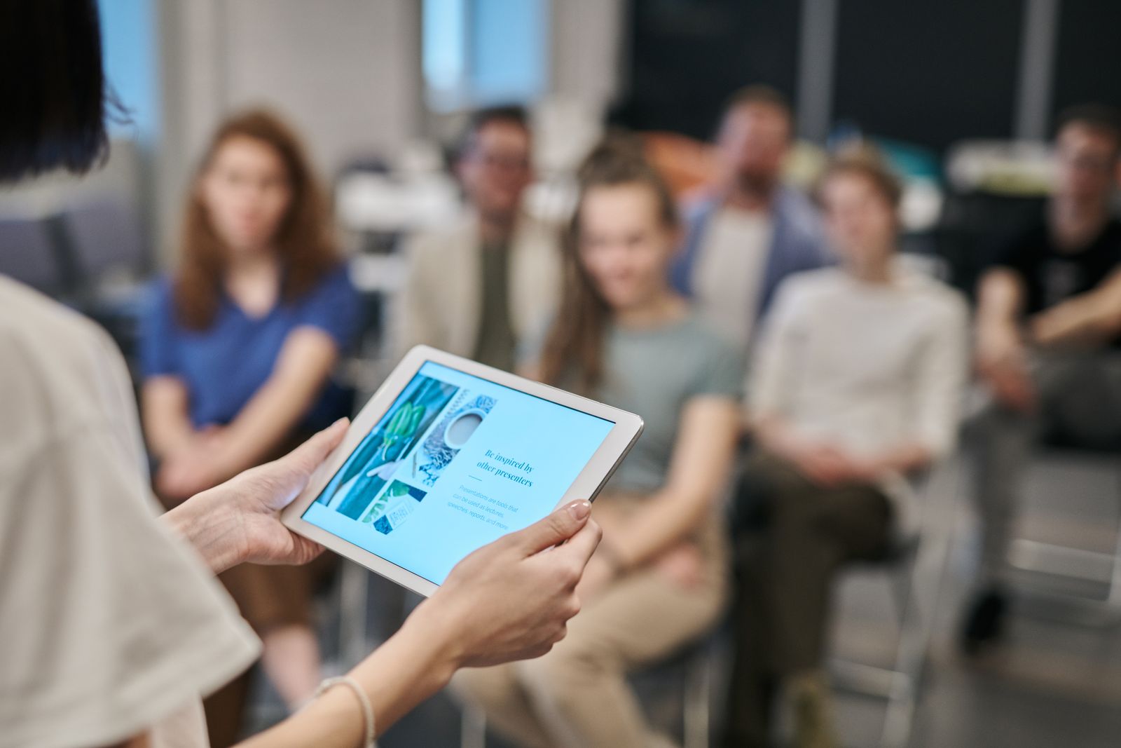 Teilnehmende eines Seminars, im Vordergrund ein Tablet in zwei Händen