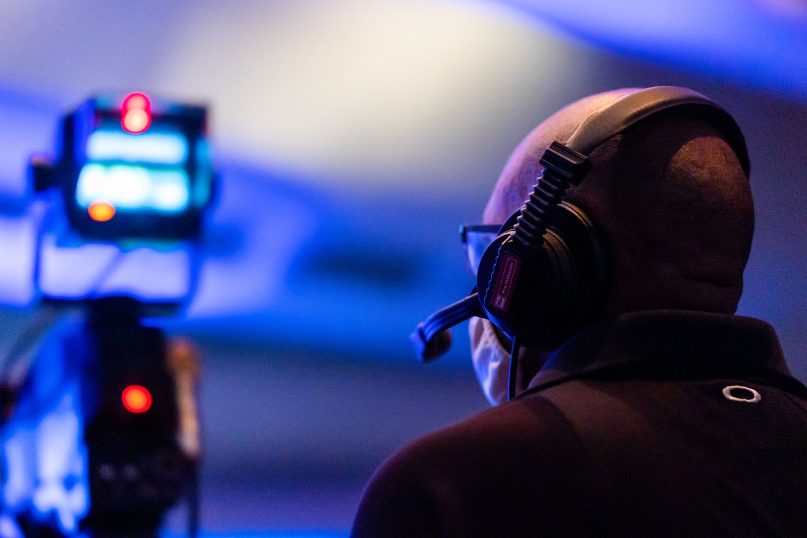 Mann mit Headset überwacht eine Veranstaltung in blauem Bühnenlicht