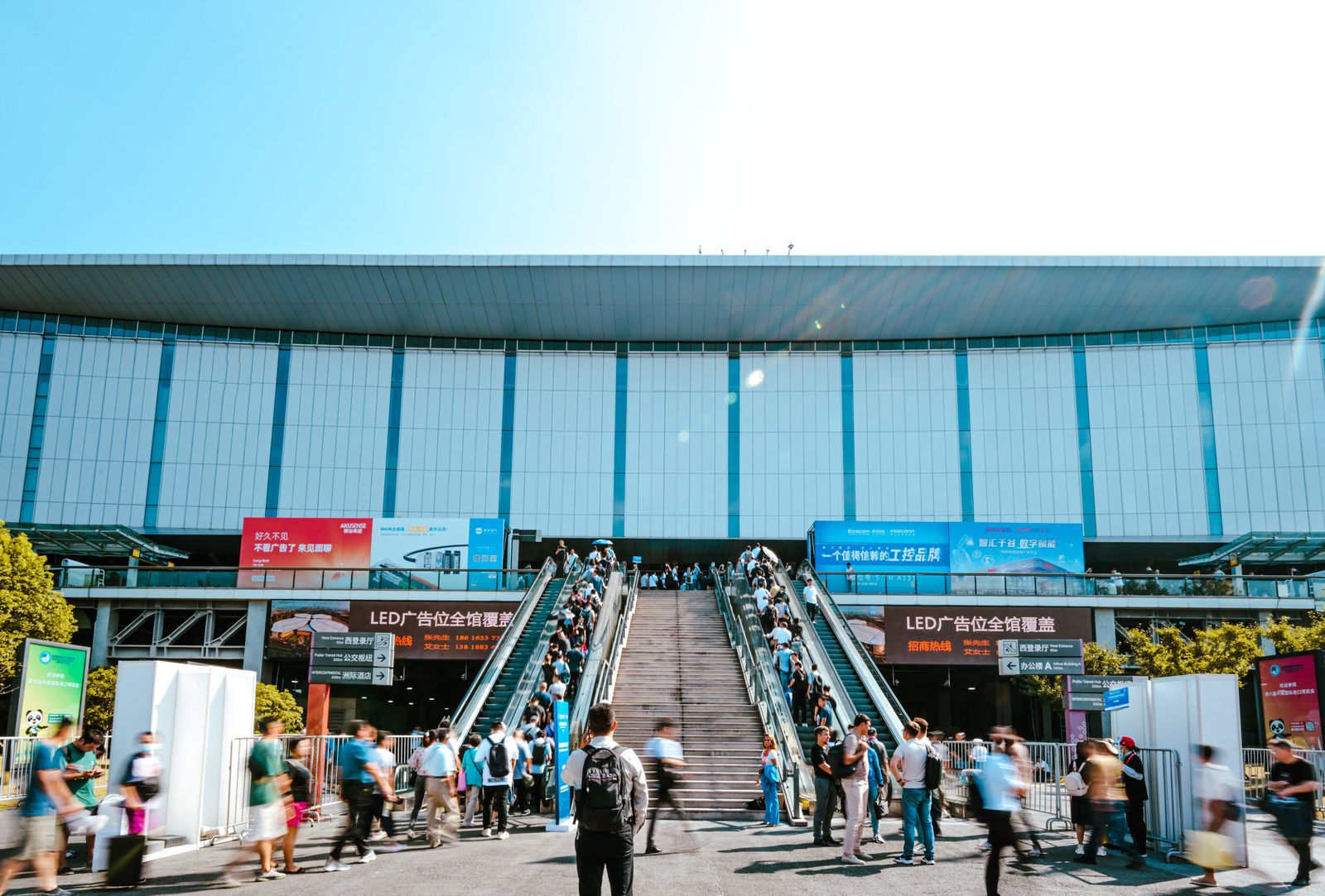 Menschen strömen über Rolltreppen in ein großes Messezentrum