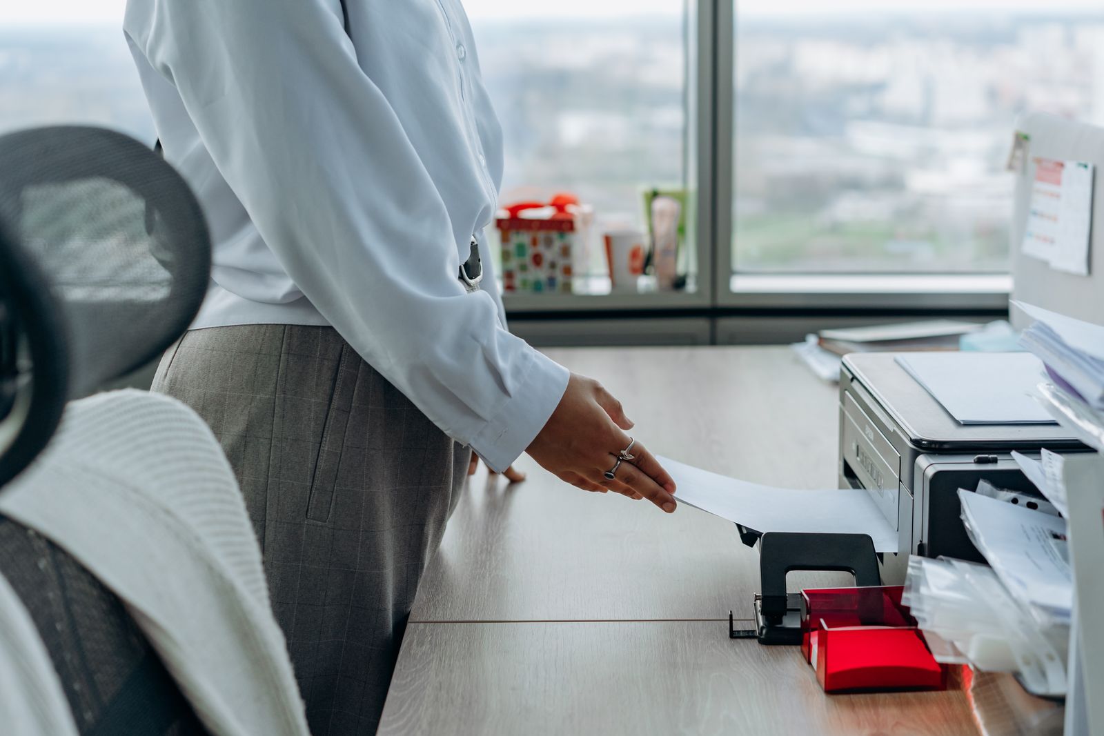 Person nimmt einen Ausdruck aus einem Drucker auf einem Bürotisch