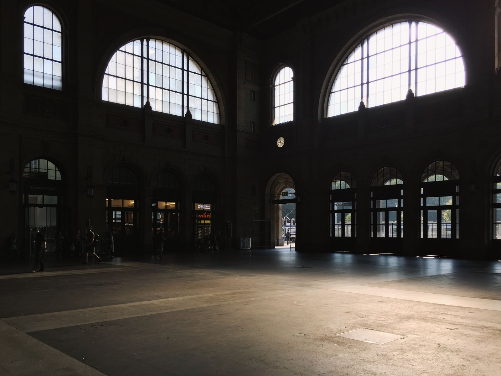 Leere Halle mit großen Bogenfenstern, durch die Sonnenlicht fällt