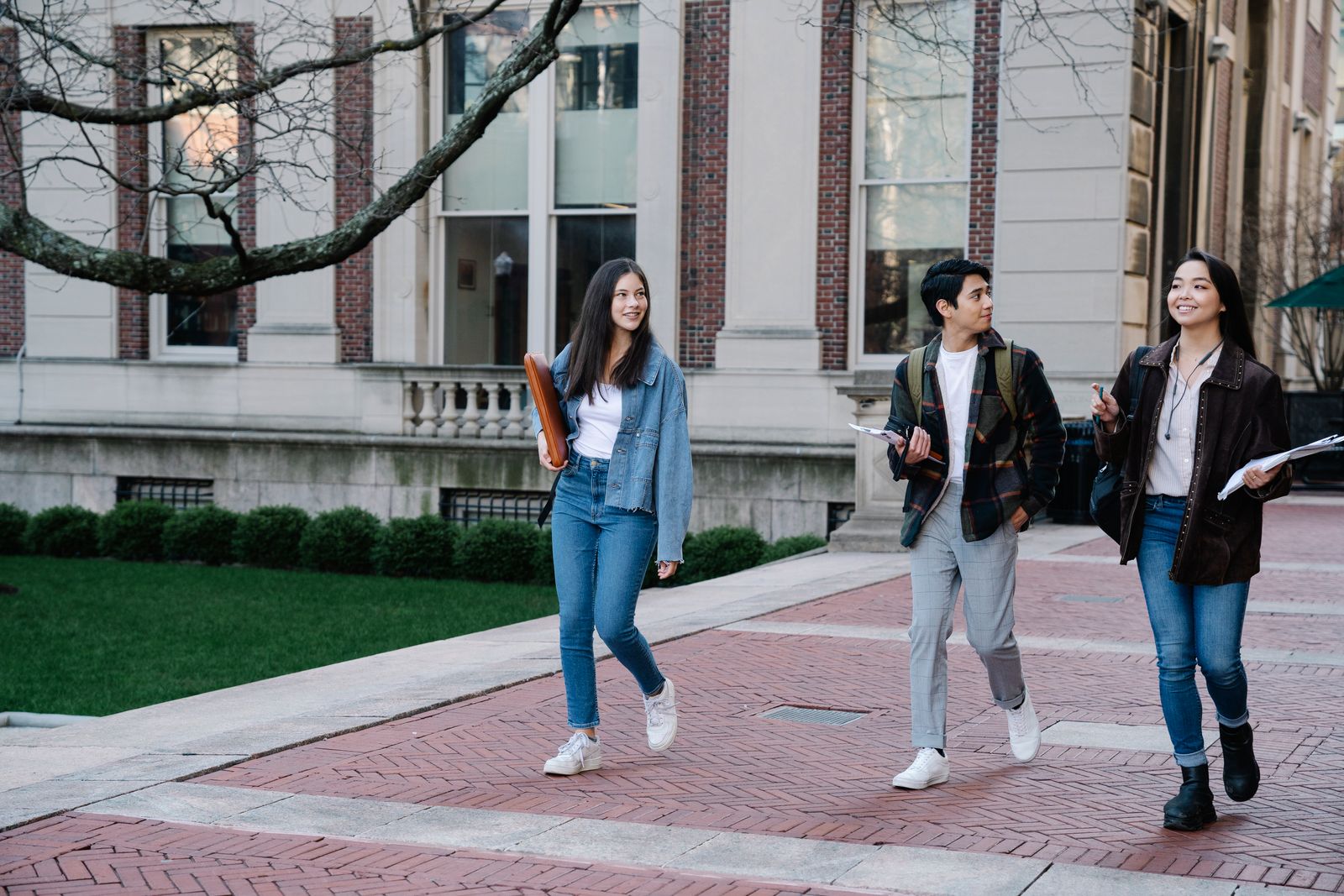 Drei Studierende gehen über einen Weg auf dem Campus