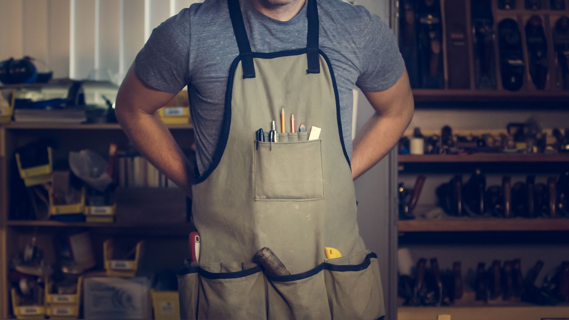 Handwerker in Arbeitsschürze mit Werkzeug in einer Werkstatt