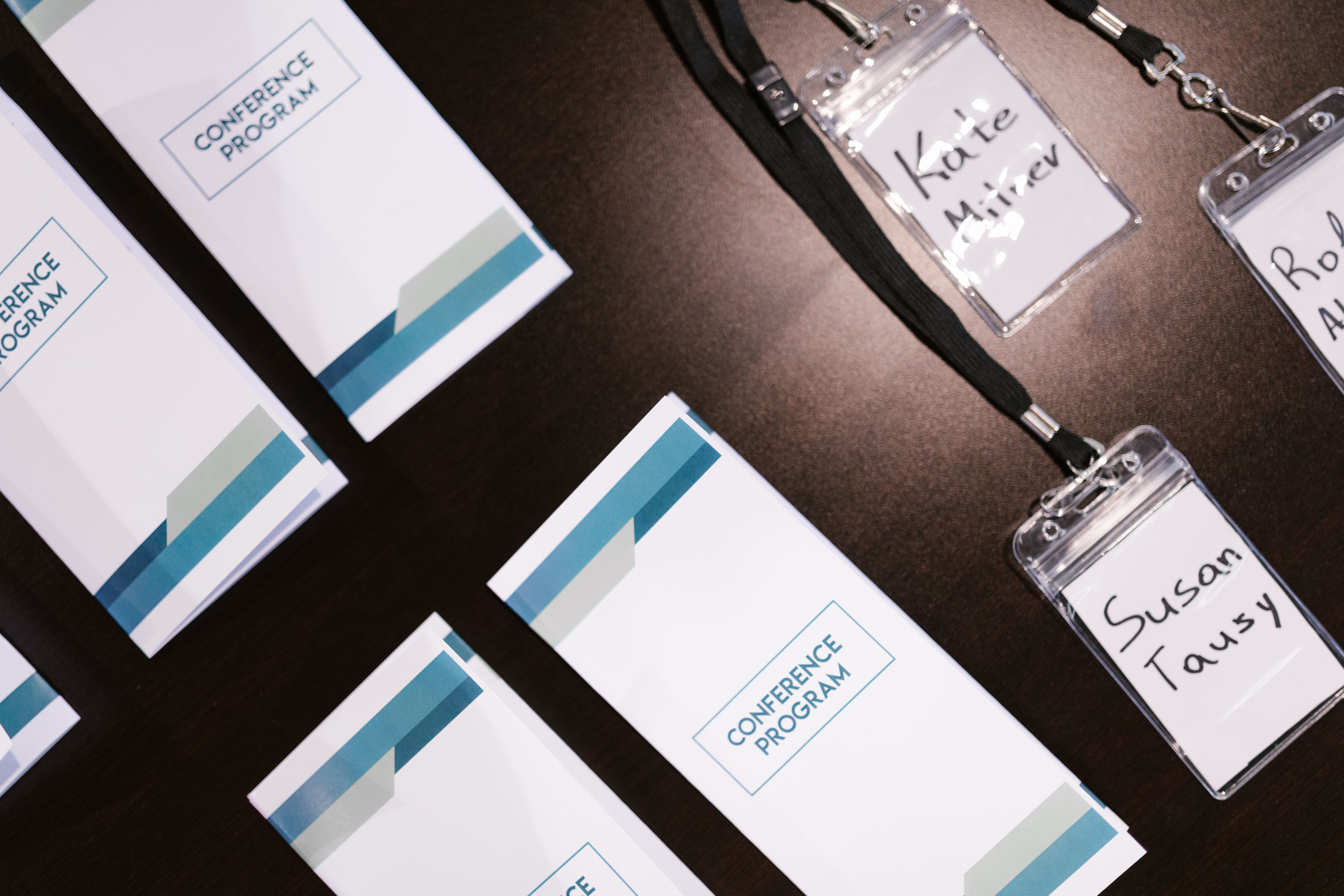 Konferenzprogramme und Namensschilder an Bändern liegen auf einem Tisch bereit