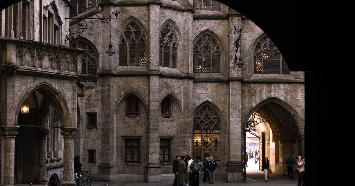 Gotischer Innenhof des Neuen Rathauses in München, durch einen Torbogen gesehen, mit Besuchern