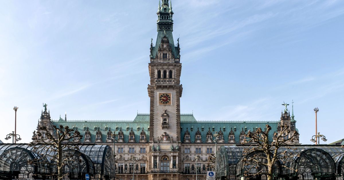 Hamburger Rathaus mit Uhrturm und kupfergrünem Dach unter blauem Himmel