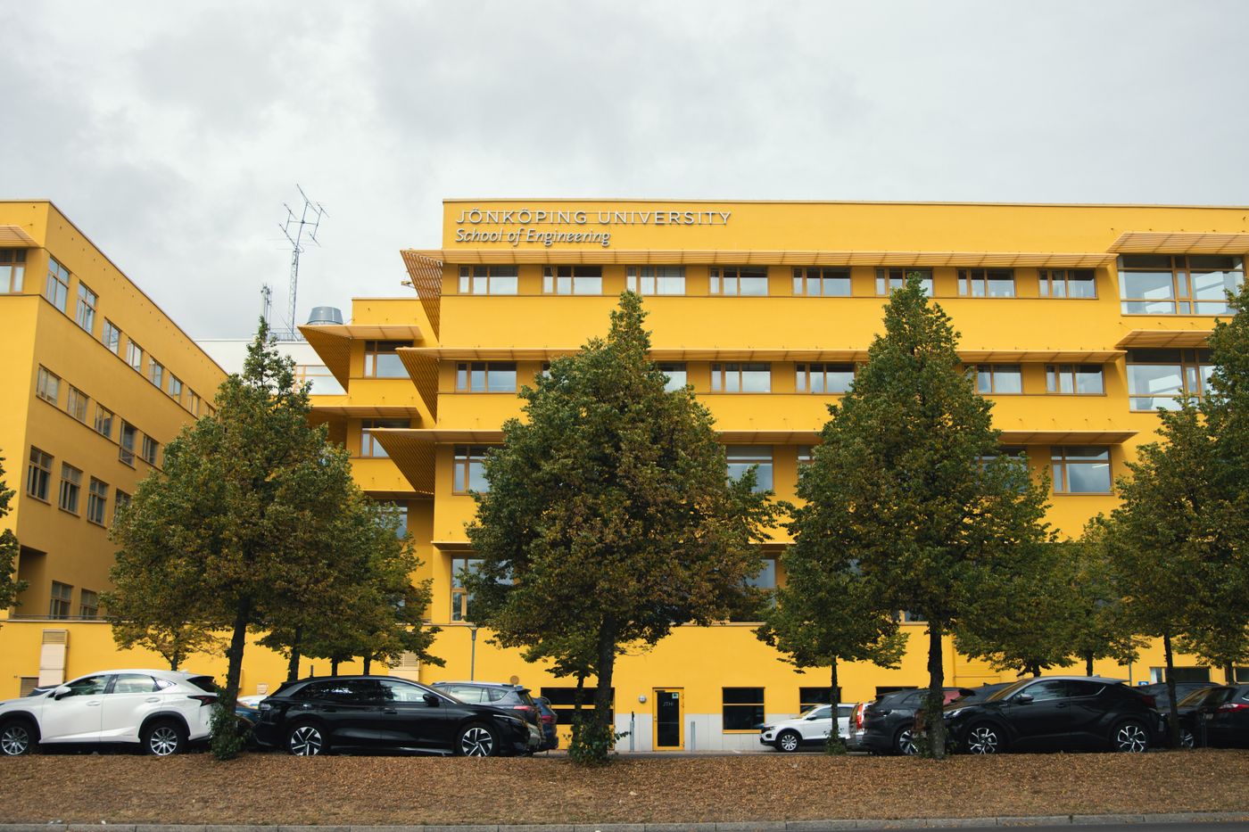Gelbe Fassade eines Hochschulgebäudes mit Fahrrädern davor
