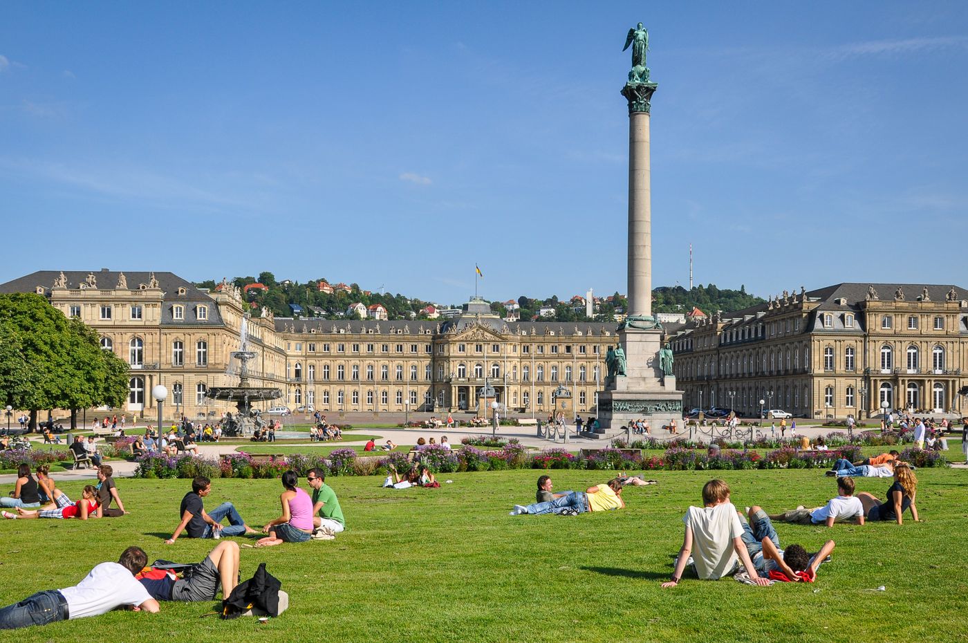 Schlossplatz in Stuttgart mit dem Neuen Schloss und Menschen auf der Wiese bei Sonnenschein
