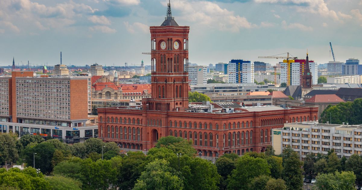 Rotes Rathaus in Berlin mit Uhrturm zwischen Bäumen und Stadtgebäuden, aus der Luft gesehen
