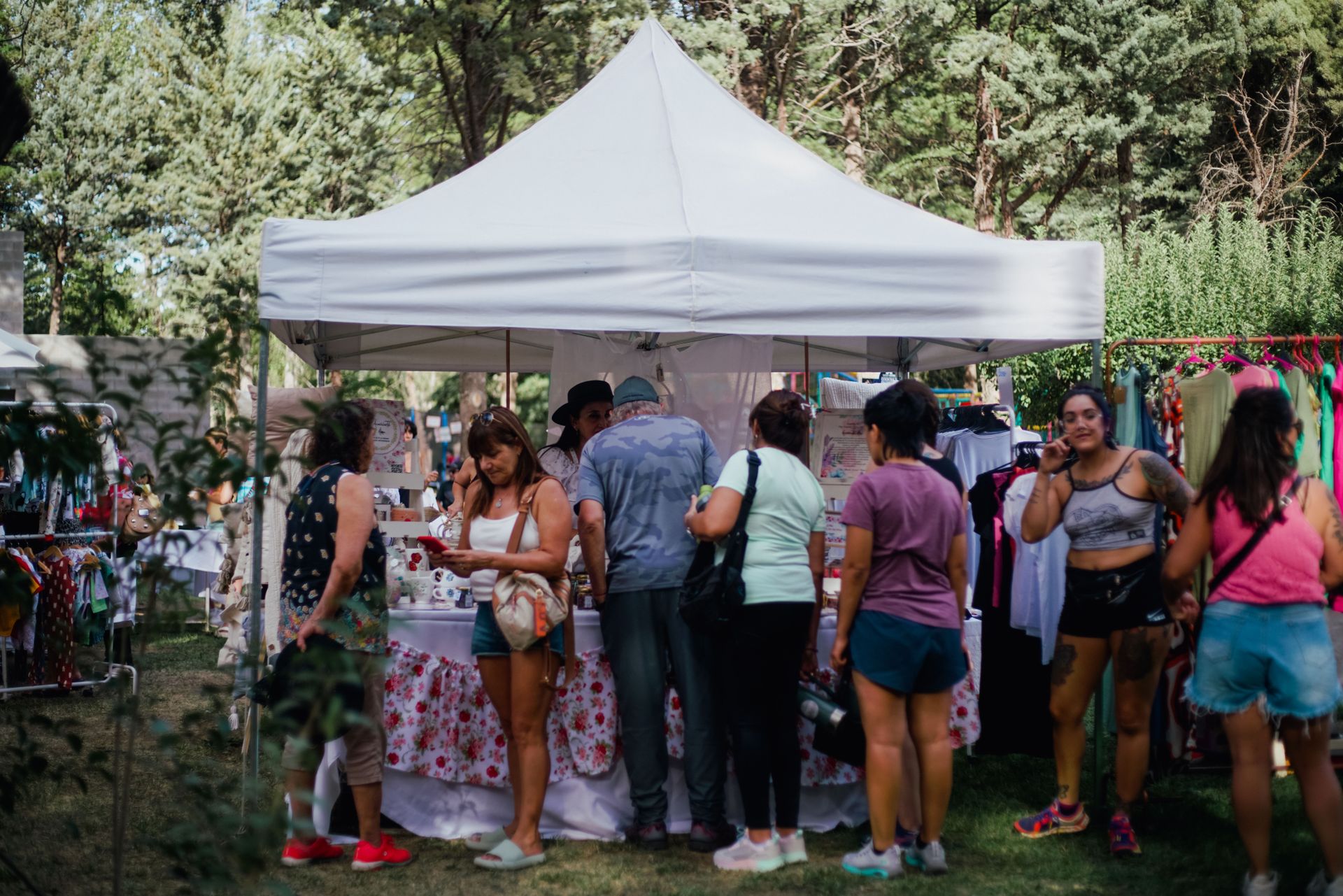 Besucherinnen und Besucher an einem Stand unter einem weißen Zelt im Freien