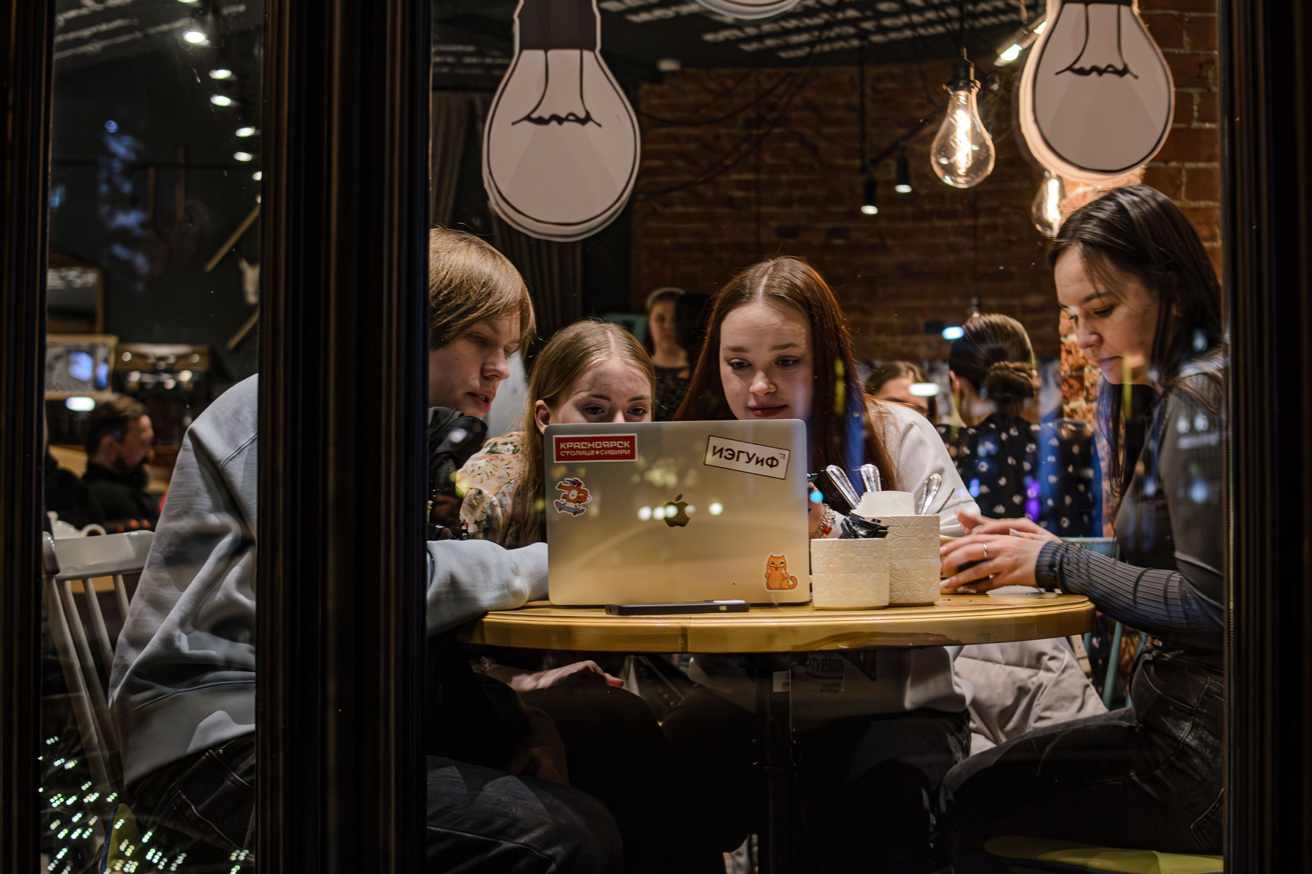 Kleine Gruppe arbeitet abends gemeinsam an Laptops an einem Tisch