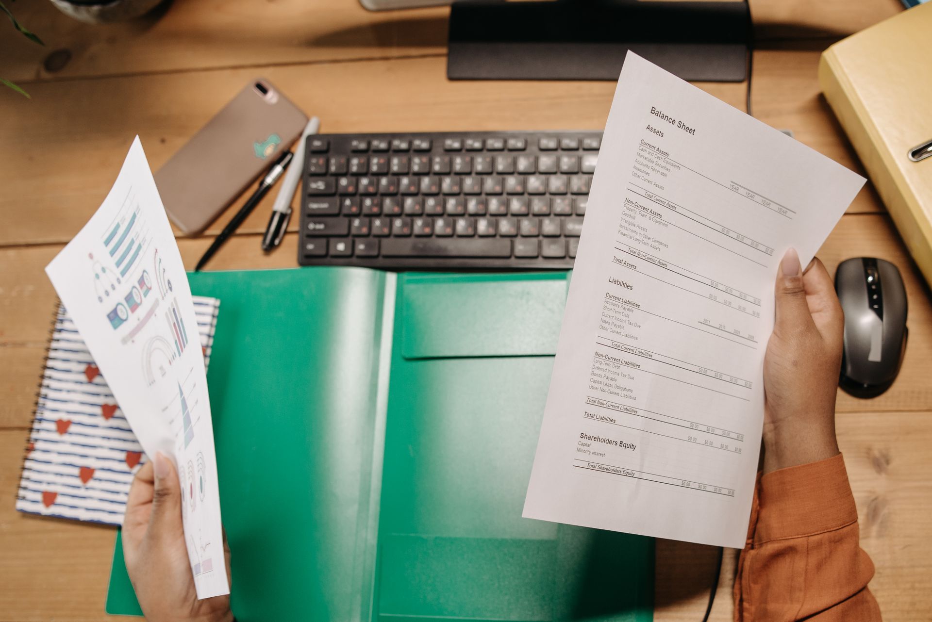 Hände prüfen Abrechnungsunterlagen an einem Schreibtisch mit Tastatur