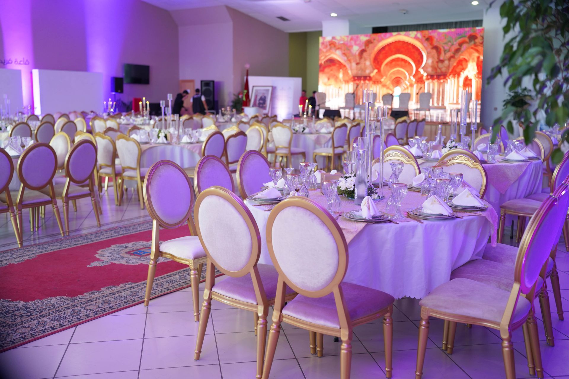 Festlich eingedeckter Saal mit runden Tischen und Bühne für eine Gala
