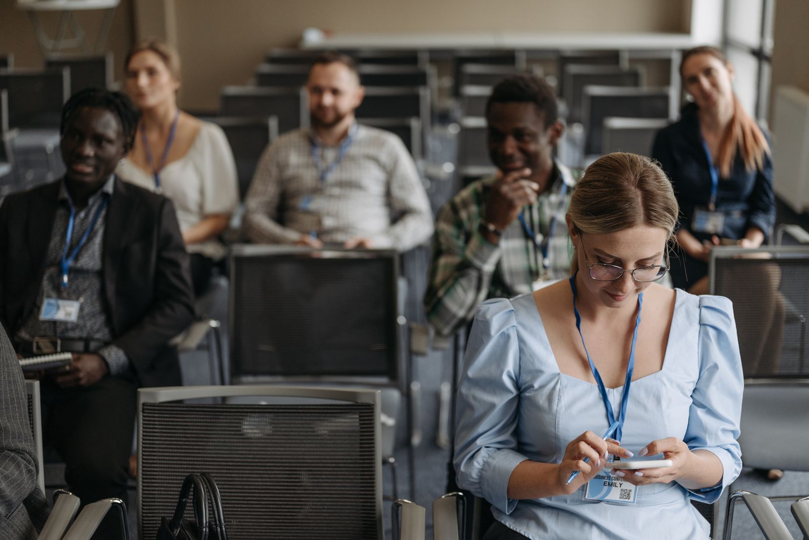 Teilnehmende eines Seminars nutzen im Tagungsraum ihre Smartphones