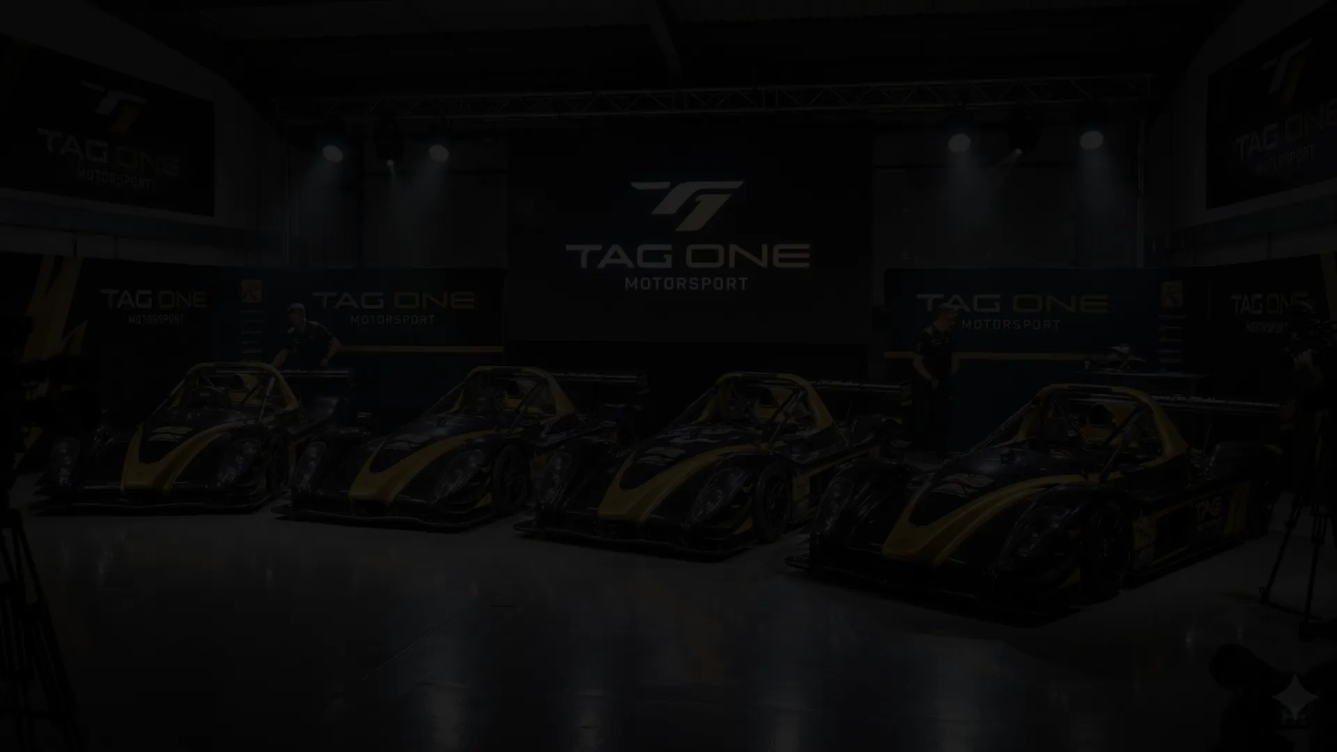 Quatre Radical SR3 XXR de Tag One Motorsport alignées dans le hangar sous le logo TAG ONE