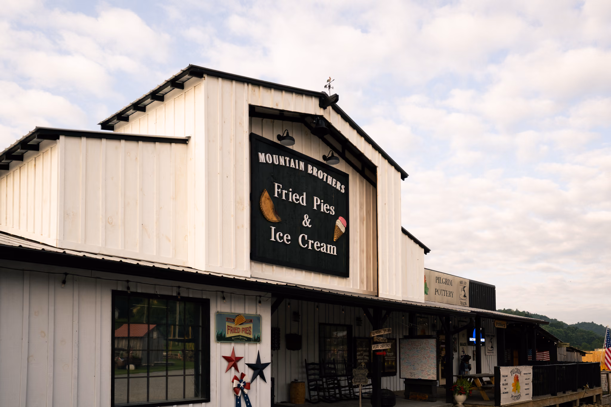 Front entrance of Mountain Brothers General Store with signs advertising delicious creamy ice cream and golden crispy fried pies, decorated with flower decorations and welcome signs.