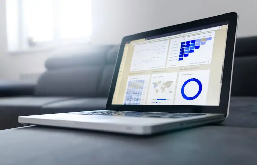 Laptop on sofa displaying charts and graphs on a data analytics dashboard.