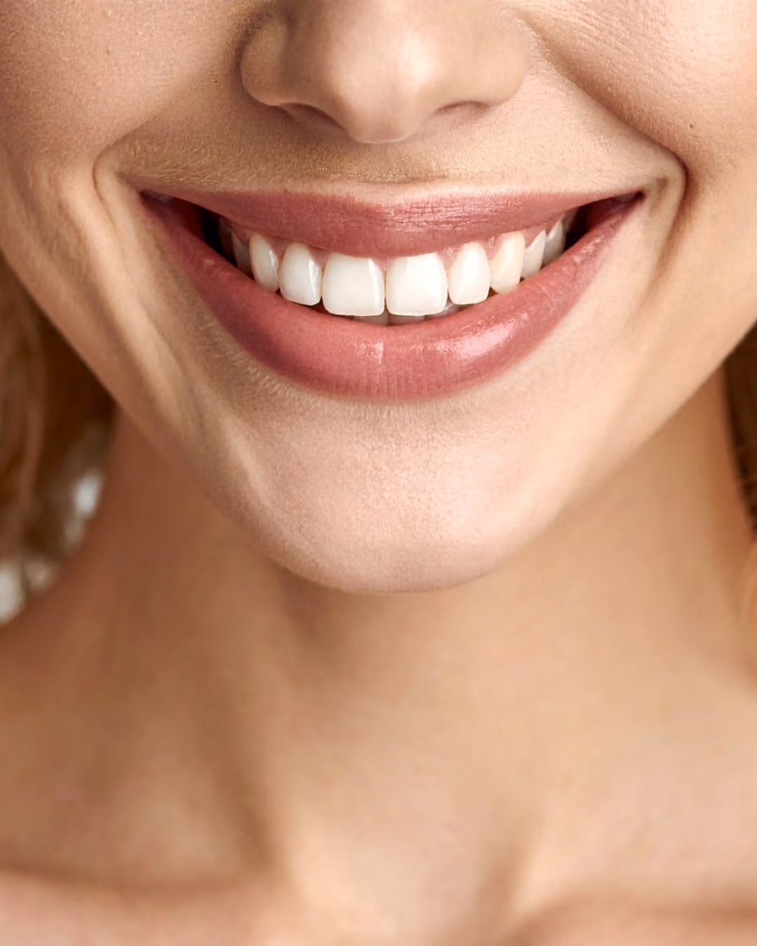 Smiling woman with short black hair and smooth skin against a plain gray background.