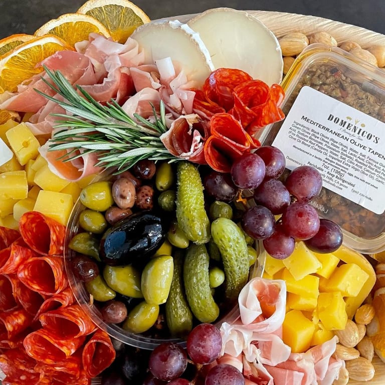 A Milkfarm charcuterie and cheese spread with olives, grapes, prosciutto, salami, and Mediterranean tapenade